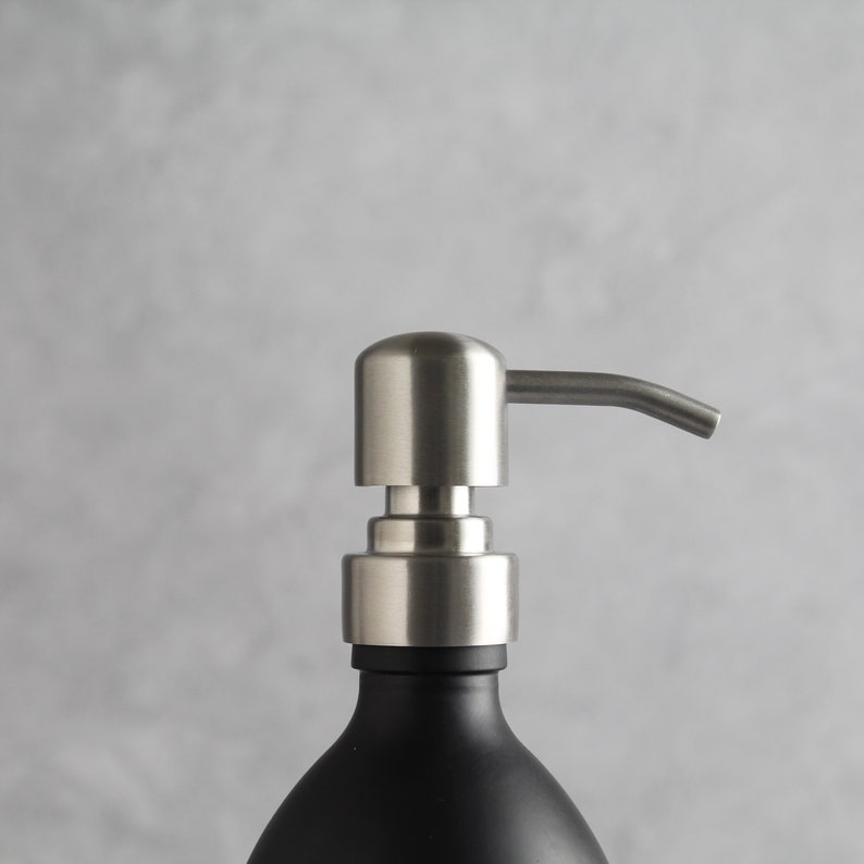 May include: A stainless steel soap dispenser pump with a black glass bottle. The pump has a long, curved spout.