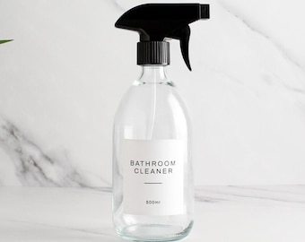 May include: Clear glass spray bottle with a black trigger and a white label that reads "BATHROOM CLEANER" and "500ml". The bottle is designed for cleaning products and has a minimalist aesthetic.