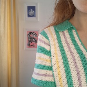 Puede incluir: Una camisa de crochet a rayas verdes, blancas, amarillas y moradas con cuello.