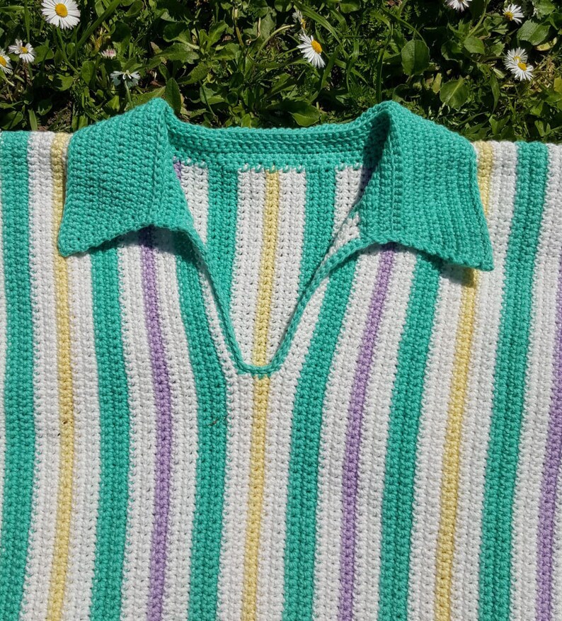 Puede incluir: Un top de crochet a rayas con un esquema de colores verde, blanco, amarillo y morado. El top tiene un cuello en V y un cuello.