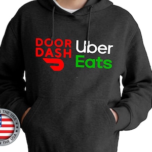 May include: A dark grey hoodie with the text "DOOR DASH Uber Eats" in red, white, and green. The DoorDash logo is a red and white stylised arrow.