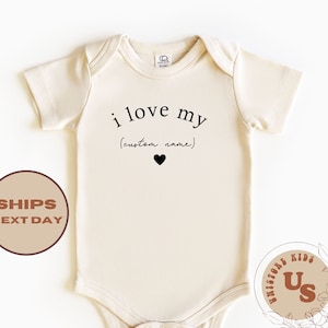 May include: A cream-colored baby onesie with short sleeves and a black print that reads "i love my (custom name)" with a small black heart.