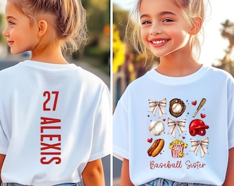 Può includere: T-shirt bianca con un design a tema baseball. La parte anteriore presenta grafiche legate al baseball e la scritta "Baseball Sister". Il retro mostra il numero 27 e il nome "Alexis" in rosso.