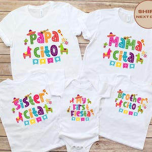 以下が含まれることがあります： カラフルなフィエスタをテーマにしたグラフィックがプリントされた白いTシャツとボディスーツ。Tシャツには「Papa Cito」、「Mama Cita」、「Sister Cita」、「Brother Cito」と書かれています。ボディスーツには「My First Fiesta」と書かれています。