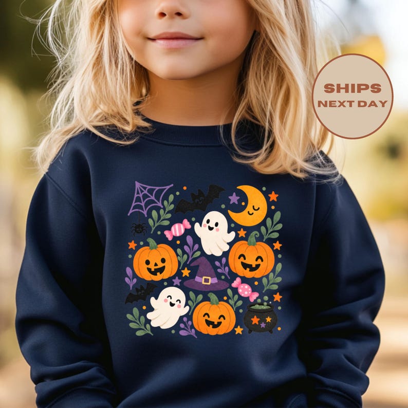 Puede incluir: Una sudadera azul marino de manga larga con un estampado gr&aacute;fico colorido con tem&aacute;tica de Halloween. El dise&ntilde;o incluye calabazas naranjas sonrientes, fantasmas blancos, un sombrero de bruja morado, una luna creciente amarilla, murci&eacute;lagos, dulces y una telara&ntilde;a.