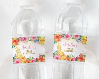 Può includere: Due bottiglie d'acqua in plastica trasparente con etichette personalizzate. Le etichette presentano un tema tropicale con ananas, fiori e vegetazione. Il testo sulle etichette recita "Amelia's First Birthday".
