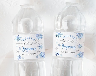 Peut inclure: Deux bouteilles d'eau en plastique transparent avec des étiquettes sur le thème des flocons de neige bleus et argentés qui disent "Melted Snow Benjamin's 1st Birthday".