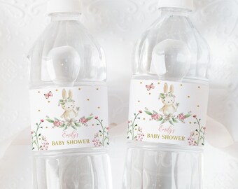 May include: Two clear plastic water bottles with personalized labels. The labels feature a watercolor illustration of a bunny rabbit with pink flowers and gold accents. The text on the labels reads "Emily's Baby Shower".