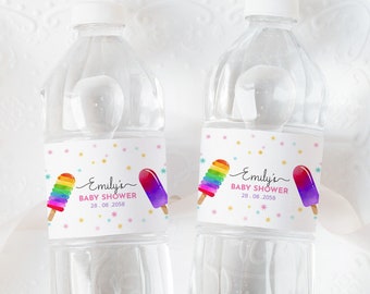 May include: Two clear plastic water bottles with personalized labels. The labels are pink, blue, and white with a rainbow and purple popsicle design. The text on the labels reads "Emily's Baby Shower 28.08.2023".