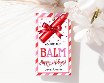 May include: A Valentine's Day gift tag with a red lipstick illustration and a red bow. The tag has a white background with red and pink stripes and hearts. Text on the tag reads "YOU'RE THE BALM Happy Holidays! Love, Amelia."