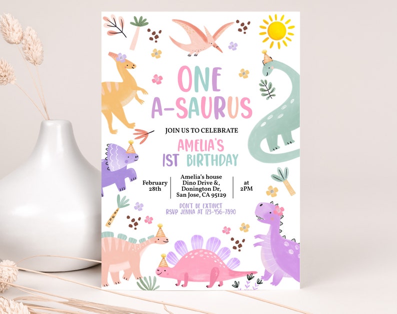 May include: A colorful invitation for a first birthday party with a dinosaur theme. The invitation features a variety of dinosaurs in pink, purple, green, and orange, along with flowers, leaves, and a sun. The text reads "One A-saurus Amelia's 1st Birthday" and includes the date, time, and location of the party.