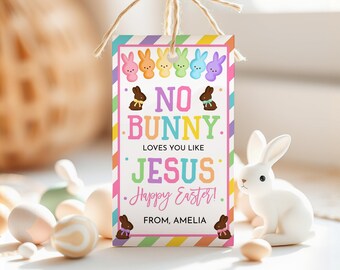 Puede incluir: Una etiqueta de regalo de Pascua rectangular con un borde a rayas de colores y el texto "NO BUNNY LOVES YOU LIKE JESUS Happy Easter!". La etiqueta presenta conejitos de dibujos animados y conejitos de chocolate. Una figura de conejo de cerámica blanca está en el fondo.