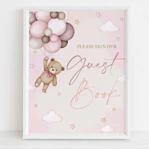 May include: A pink and brown guest book sign with a teddy bear holding balloons. The sign says "Please sign our guest book".