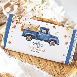 May include: A blue pickup truck with a white and orange pumpkin load, surrounded by fall leaves. The truck is on a white background with the text "Emily's Baby Shower 10.28.2058".