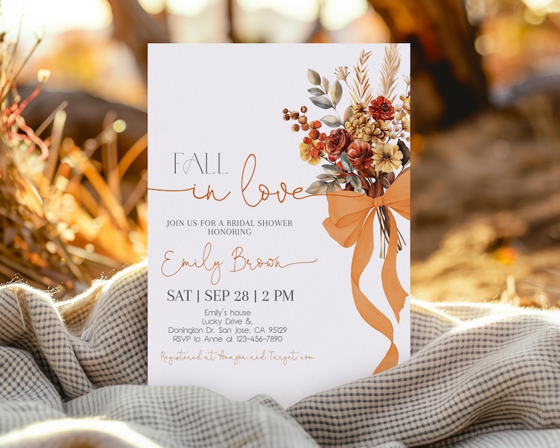 May include: A bridal shower invitation with the text "Fall in Love" and details for Emily Brook's shower. The invitation features a floral bouquet with orange ribbon and is set against a blurred background.
