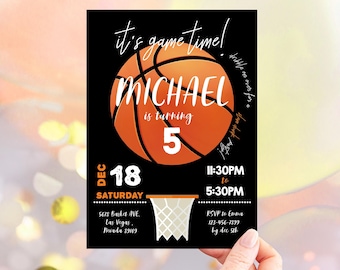 May include: A black and orange basketball birthday invitation for a boy turning five. The invitation features a basketball with the name "MICHAEL" and the number "5" on it. The text "It's game time!" is written in white on a black background. The invitation also includes the date, time, and RSVP information.