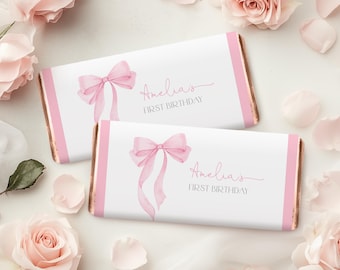 May include: Two pink and white chocolate bar wrappers with a pink bow and the text "Amelia's First Birthday" on each.