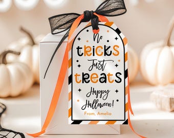 Puede incluir: Una caja de regalo blanca con una etiqueta temática de Halloween. La etiqueta dice "No tricks Just treats Happy Halloween! From, Amelia" en negro y naranja. La caja está atada con una cinta negra y naranja, con calabazas blancas en el fondo.
