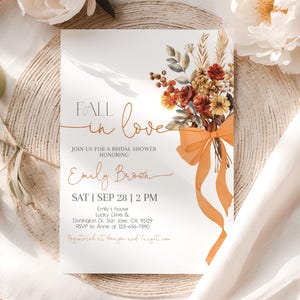May include: Bridal shower invitation with the words "Fall in Love" in elegant script. The invitation features a floral bouquet with orange ribbon and text details including the name "Emily Brown" and event information.