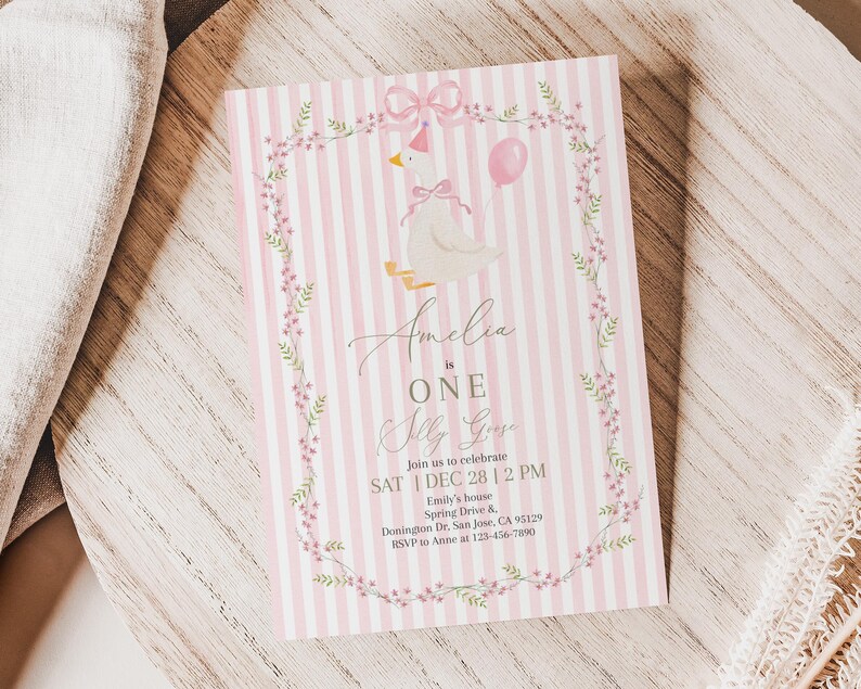 May include: A pink and white striped invitation card with a watercolor illustration of a goose wearing a bow and holding a balloon. The text reads "Amelia is ONE" and includes event details.