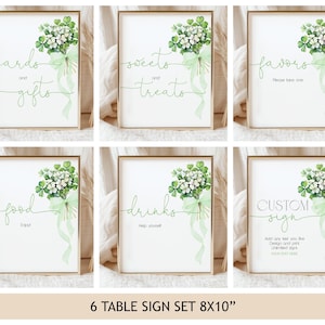 May include: A set of six framed signs with gold borders. Each sign features a watercolor floral design with green shamrocks and text such as "cards and gifts," "sweets and treats," and "favors." The signs are 8x10 inches.
