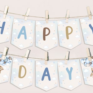 May include: A blue and brown banner with the words "HAPPY DAY" strung on a twine with clothespins. Each letter is on a separate pennant with a watercolor background of clouds and stars. The pennants with the letters "H" and "Y" have a teddy bear holding balloons.