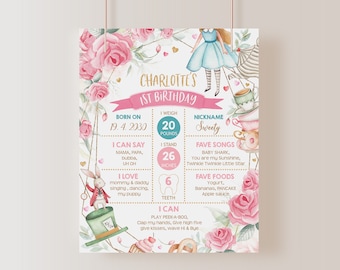 May include: A pink and gold first birthday milestone chart for a baby girl named Charlotte. The chart features a whimsical Alice in Wonderland theme with illustrations of teacups, a rabbit, and a Mad Hatter's hat. It includes details like her birthdate, weight, height, favourite songs, foods, and things she can do.