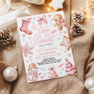 May include: Pink and white invitation card with a gingerbread theme. The card says "Two Sweet" and "Amelia's 2nd Birthday". The card has a gingerbread man, a gingerbread stocking, a gingerbread star, a gingerbread tree, and a snowman.