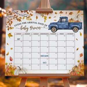 Puede incluir: Un calendario de baby shower con una camioneta azul que transporta calabazas. El calendario está decorado con hojas de otoño y calabazas. El texto dice "¡Adivina la fecha de llegada del bebé Brown!" e incluye una cuadrícula de calendario con la fecha de vencimiento en octubre.