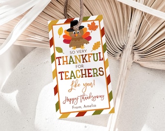 Può includere: Un'etichetta regalo per il Ringraziamento con un tacchino dei cartoni animati con un cappello e la scritta "So Very Thankful for Teachers Like you!" in arancione, verde e marrone. L'etichetta è rettangolare con un bordo a righe e uno spago marrone.