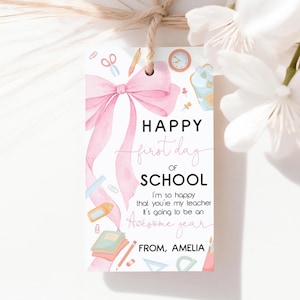 May include: A white gift tag with a pink watercolor bow and the text "HAPPY first day OF SCHOOL". The tag includes school-themed illustrations and the message "I'm so happy that you're my teacher. It's going to be an Awesome year. From, Amelia."