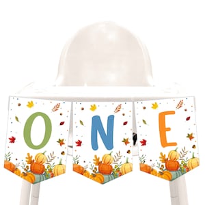 Puede incluir: Una pancarta para silla alta con temática otoñal. La pancarta dice "ONE" en letras verdes, azules y naranjas. La pancarta está decorada con calabazas, hojas y bellotas.