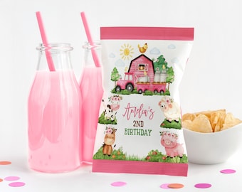 May include: A party scene with a pink theme, featuring a bag of crisps, two bottles of pink liquid with straws, and a bowl of crisps. The crisp packet has a farm design with a tractor, barn, and animals, with the text "Amelia's 2nd Birthday".