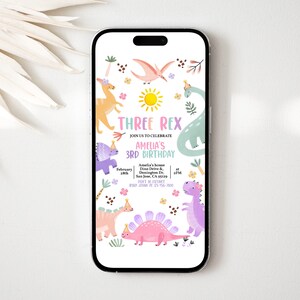 Op de afbeelding: Een smartphone toont een verjaardagsuitnodiging met een dinosaurus thema. De tekst luidt "THREE REX" en "AMELIA'S 3RD BIRTHDAY". De uitnodiging bevat illustraties van dinosaurussen, een zon en bloemmotieven.