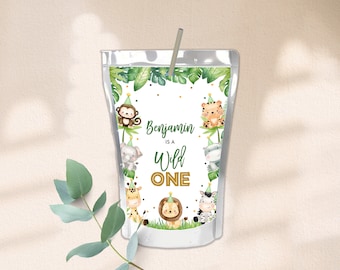 Puede incluir: Una caja de jugo blanca con un tema de jungla verde. Presenta una variedad de animales con sombreros de fiesta, incluyendo un mono, un tigre, una cebra, una jirafa y un elefante. El texto en la caja dice "Benjamin is a Wild One".