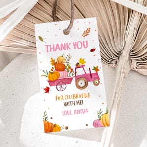 May include: Pink and white thank you tag with a watercolour illustration of a pink tractor carrying pumpkins. The text reads "Thank You for celebrating with me! Love, Amelia".