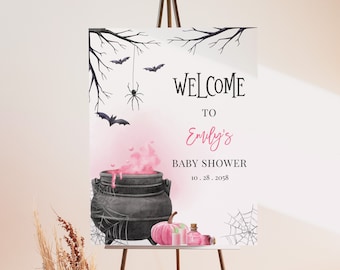 May include: A welcome sign for a baby shower with a pink and black Halloween theme. The sign features a cauldron with pink potion, bats, a spider, a pumpkin, and a bottle of potion. The text reads "Welcome to Emily's Baby Shower 10.28.2058".