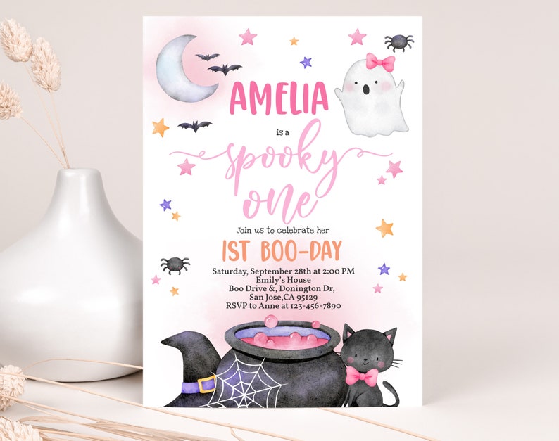 May include: A pink and purple Halloween-themed first birthday party invitation with a ghost, a black cat, a cauldron, and stars. The invitation says "Amelia is a spooky one" and includes the date, time, and location of the party.