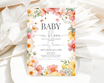 Op de afbeelding: Een baby shower uitnodiging met een bloemenontwerp. De uitnodiging is wit met roze en gele bloemen. De tekst op de uitnodiging luidt "Baby in Bloom" en bevat de datum, tijd en locatie van de babyshower.