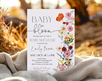 May include: A baby shower invitation with a floral design. The text reads "Baby in Bloom" and includes the date, time, and location of the event. The invitation is decorated with watercolor flowers in shades of pink, red, orange, and yellow.