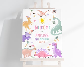 May include: Welcome to Amelia's 3rd Birthday Party sign with a colorful dinosaur theme. The sign features a variety of dinosaurs in pink, purple, green, and orange, with a sun and flowers in the background.