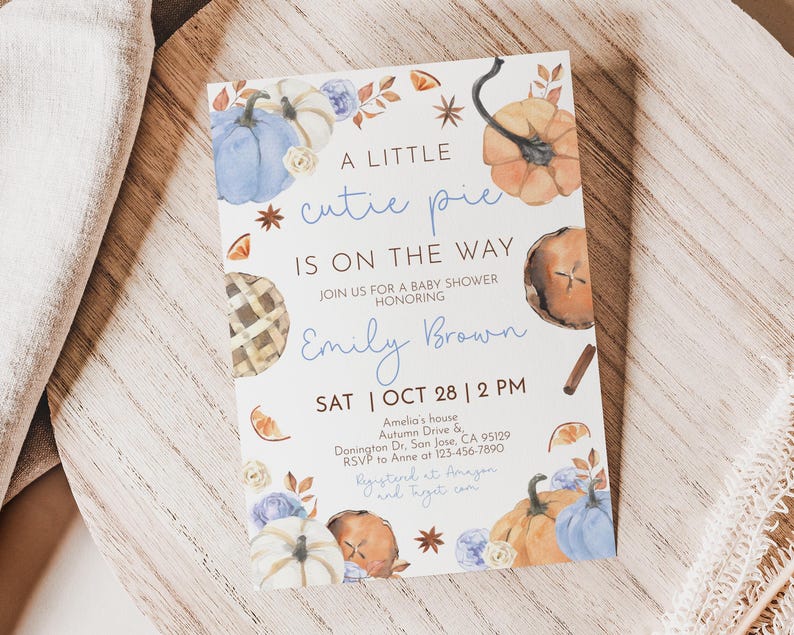 Puede incluir: Invitaci&oacute;n a un baby shower con calabazas de acuarela, tarta y detalles florales. El texto dice "A Little Cutie Pie Is On The Way" con el nombre de la homenajeada, la fecha, la hora y el lugar. Sobre una superficie de madera.
