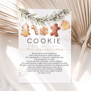 May include: A white card with watercolor illustrations of gingerbread cookies and greenery. The card reads "COOKIE kit instructions" in elegant script, with instructions below on how to decorate cookies.