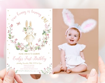 Puede incluir: Una invitación de cumpleaños rosa y blanca con una ilustración de acuarela de un conejito con una corona de flores. La invitación dice "some bunny is turning one" e incluye detalles para la fiesta del primer cumpleaños de Emily.