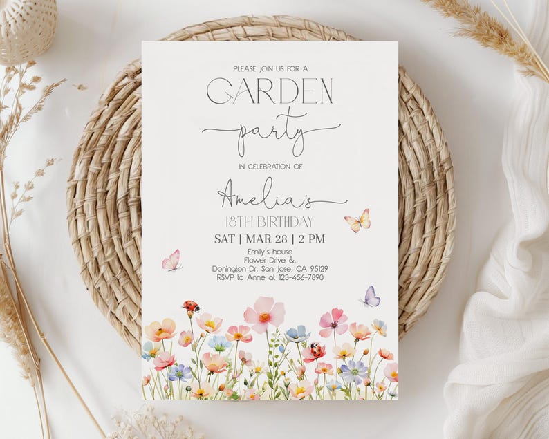 以下が含まれることがあります： 「GARDEN party」と「Amelia's 18th Birthday」の文字が入った、クリーム色のガーデンパーティーの招待状。ピンク、青、黄色の水彩画の花と蝶で飾られています。招待状は織りのプレースマットの上に置かれています。