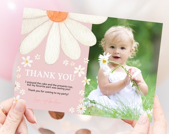 May include: Pink thank you card with a white daisy design and a photo of a baby girl holding a bouquet of daisies. The text on the card reads "Thank You. I enjoyed the cake and the presents too, but my favorite part was seeing you! Thank you for coming to my party! Love Amelia."