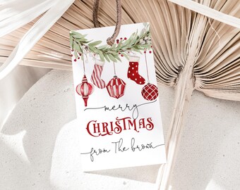May include: A rectangular gift tag with a brown leather string. The tag features watercolor illustrations of Christmas ornaments and stockings, with the words "merry CHRISTMAS from The brown" in red and black script.