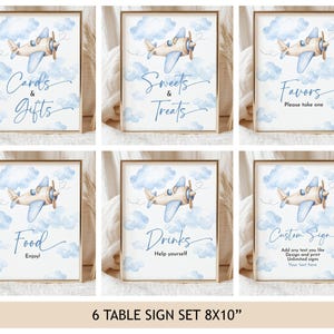 May include: A set of six rectangular table signs featuring a watercolor illustration of a light blue and tan airplane flying among soft blue clouds. The signs display the text: Cards & Gifts, Sweets & Treats, Favors, Food, Drinks, and Custom Sign.