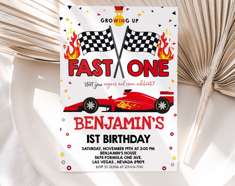 May include: A red, white and black birthday invitation for a 1st birthday party with a racing car theme. The invitation features a red racing car with flames and chequered flags. The text on the invitation reads "Growing Up Fast One" and "Benjamin's 1st Birthday".