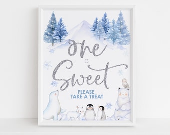 May include: A white sign with a blue watercolor winter scene. The text "One is Sweet" is written in silver glitter. The sign also says "Please take a treat". There are images of a polar bear, a penguin, a seal, and a fox.